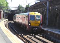 334 001 <I>Donald Dewar</I> passes through Bridgeton on a warm 17 June with a Larkhall to Dalmuir service. It is passing at no great speed, fooling people on the platform into thinking that it's a stopping service then, when it's clear that it's not going to stop, obliging them to pretend to each other that they knew this all along. For the reopening of the former Bridgeton Cross station in 1979 it was presumably thought a good idea to spell out 'Bridgeton' between double arrows in individually framed letters, but they are simply too far apart for it to be effective. <br>
<br><br>[David Panton 17/06/2010]