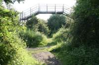 View east on 27 June 2010 along the route of the direct goods lines that ran between Niddrie West (behind camera) and the ECML. The location is around 250m short of the former Wanton Walls Junction where the Lothian Lines from Leith and Portobello came in from the left to join the route. The old footbridge seen here just to the north of Newcraighall village has long been out of use with the right of way having reverted to the original footpath seen crossing the trackbed in the foreground.<br>
<br><br>[John Furnevel 27/06/2010]