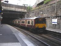 'Charing Cross: alight here for Mitchell Library and King's Theatre' <br>
says the sign. An older version, hidden in the gloom of the disused end of the other platform shows its age by adding 'Strathclyde Regional Council Headquarters': regions were abolished in 1996. 318 256 emerges from Finnieston Tunnel on 19 June with an Airdie service. It will come to a stop with the front of the train already in the next tunnel, Charing Cross.After that a very brief gap before Queen Street Lower Level station then... another tunnel. No wonder strangers think this is 'the underground'.<br><br>[David Panton 19/06/2010]