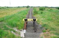 The 'Watsonhead' coal loading pad was built just shy of the former Wishaw and Coltness terminus at Morningside when a short section of the former line was re-opened from Stirling Road. Historically the W&C line was continued on ultimately to Bathgate by the Wilsontown, Morningside and Coltness (the uneasy relationship demonstrated by the fact there were two Morningside stations on either side of a roadbridge for the two companies, later the Caley and NB). The loading pad was to be removed after Watsonhead opencast was worked out but is still in place, albeit somewhat overgrown, presumably due to a number of other opencast possibilities in the area. The view looks west towards Morningside Junction at Stirling Road. Formerly the branch to the Chapel Colliery was to the left, the passenger line to Newmains to the right and Morningside (Caledonian) station and a branch to the Allanton Brickworks and collieries behind the camera. [See image 29594]<br><br>[Ewan Crawford 27/06/2010]