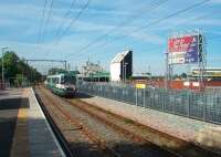 Significant recent changes to the station at Old Trafford have seen the platforms altered to a staggered arrangement and the subway replaced by a level crossing. There are now also barriered queueing areas on both platforms to cope with crowds from the nearby cricket ground. Metrolink tram 1007 leaves for Manchester passing the old scoreboard and its modern replacement. [See image 21085] for a direct comparison with the same scene two years previously.<br><br>[Mark Bartlett 30/06/2010]