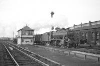 Stanier 8F 2-8-0 no 48641 brings a southbound freight past Hellifield shed in the 1960s. Following closure by BR in 1963 the shed was later used to store and renovate exhibits earmarked for the National Railway Museum in York, which opened in 1975. The old shed was subsequently demolished.<br><br>[Robin Barbour Collection (Courtesy Bruce McCartney) //]