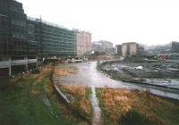 Much of the area to the north of the E&G line between Haymarket station (in the right background) and Haymarket shed used to be occupied by a rail-served coal yard, but this was abandoned in the 1990s, the rails having long gone. This view in January 1998 shows the cobbled access road and loading banks, about to be swept away in a development of office buildings. The access road was realigned to run just over the fence from the station. It was given the name 'Haymarket Yards', effectively commemorating a coal depot! [See image 30546] <br>
<br><br>[David Panton /01/1998]