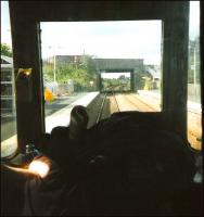 First generaton DMUs allowed you the simple pleasure of 'playing <br>
driver', provided the driver hadn't been a spoilsport and pulled down the blind behind him (admittedly necessary at night to prevent <br>
distracting reflections). It's September 1999 and there are just a <br>
couple of months left of Class 117s operating out of Edinburgh from <br>
where, for a few years, they'd been used only at peak times. With the driver's hand (and paper) in view, and watched by a figure on the bridge, the unit comes to a halt at Rosyth with a northbound service. <br>
<br><br>[David Panton /09/1999]