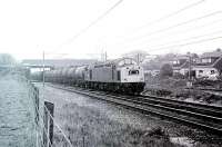 An unidentified Class 40 hustles a train of oil tanks along the Up Slow line through the site of Balshaw Lane & Euxton station, which had closed in 1969 and been cleared away for the 1972 electrification. By 1998 a new (and renamed) station had opened at this location. [See image 29818] for a Then and Now comparison that illustrates the positive developments at this site.<br><br>[Mark Bartlett //1981]