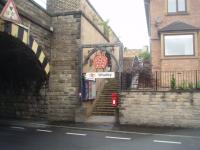 The ornate arch at the street level entrance to Whalley, proudly displaying Lancashire's Red Rose, was created when the station reopened to passengers in 1994 after being closed for 32 years. Half way up the stairs is a white tiled subway under the line that allows access to the other platform. Behind the camera the low bridge joins directly on to the 48 arch Whalley viaduct [See image 20585]. <br><br>[Mark Bartlett 21/07/2010]