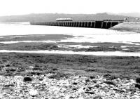 A southbound DMU crossing the River Kent estuary in the north east corner of Morecambe Bay in October 1983. View is west from The Promenade at Arnside, looking towards Grange-over-Sands.<br><br>[John Furnevel 07/10/1983]