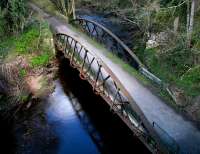 The sun catches the rail bridge over the North Esk at Auchendinny, seen here looking along the trackbed towards Penicuik from above the tunnel in April 2004. <br><br>[John Furnevel 07/04/2004]