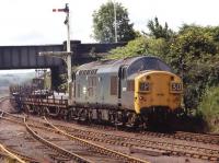 6771 brings a train of bogie bolsters loadedwith steel from Consett downhill past South Pelaw Junction heading for Tyne Yard on 28 June 1971. In the foreground are the rusting rails of the formerdirect route to Tyne Dock via Washington.<br><br>[Bill Jamieson 28/06/1971]