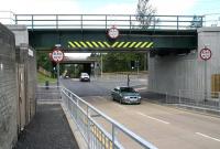 Following a significant period of closure, the former single-file B8046 at Uphall station has reopened as a two lane road. There is now a turn-off to the right between the railway and M8 bridges leading to the recently cleared area on the north side of the station, where further development work is pending. View north through the bridges on 27 July 2010. [See image 28761] <br><br>[John Furnevel 27/07/2010]