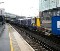 Marshalled in the centre of a Dollands Moor - Wembley freight on 25 August 2010, the first of the new ScotRail emus, no 380106, passes north through a rain-soaked Shepherd's Bush station on the West London Line.  <br><br>[Michael Gibb 25/08/2010]