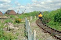 In May 1989, 26041 and 7 molasses tanks slowly rounded the curve close to Ladyburn Junction after leaving the James Watt Dock United Molasses depot. This short branch was awkward for a number of reasons; there was a steep gradient, a tight 180 degree curve, reversal to reach the loading area (okay, not inconvenient for arriving trains) and gravity shunting was required to allow the locomotive to round loaded trains as there was no loop. Also the track was beginning to go a bit 'square' on the curve as can be seen here. The locomotive had just crossed the (now) recently (25/09/2010) removed bridge over the A8.<br><br>[Ewan Crawford /05/1989]