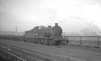 J27 0-6-0 no 65858 rumbles south over the King Edward Bridge towards Gateshead with a freight in the 1960s. The floodlights of St James' Park can be seen through the haze above the tender.<br><br>[K A Gray //]