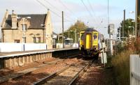 Having picked up passengers at Kirknewton station on 12 October, the driver of unit 156437 has left his cab to depress the plunger which will activate the level crossing barriers over the B7031 just behind the camera. The train is the 13.26 Edinburgh Waverley - Glasgow Central.<br><br>[John Furnevel 12/10/2010]