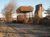 Steam age relics at Carnforth shed with the famous coaling tower that can be seen from some distance away and also the old water tower, both lit by the early sun on a very cold morning. Behind them the shed itself can be seen, with many roads now occupied by WCRC coaching stock. <br><br>[Mark Bartlett 28/11/2010]