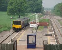 The long approach ramp to Salwick leads to a very basic station with a sparse service these days. 150146, on its way to Blackpool South, forms one of only three trains a day in each direction. View towards Kirkham and Wesham through the heat haze on this former four track main line.  <br><br>[Mark Bartlett 10/05/2008]