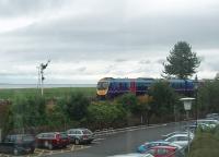 A Barrow to Manchester Airport service skirts Morecambe Bay running in to Grange-over-Sands station. 185128 is seen through the window of a cafe that overlooks the line from the promenade car park.<br><br>[Mark Bartlett 29/07/2010]