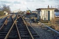 The last traffic on the (latterly) freight only line between Lenwade and Wroxham was generated by Anglian Building Products Ltd from its factory just south of Lenwade station. This is a view of the factory sidings in 1977 a few years before final closure of the line, looking south towards Attlebridge. The company's shunting locomotive is green painted Class 03 D2118 which has survived into preservation.<br><br>[Mark Dufton 13/02/1977]