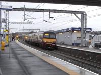 It's only 13.20 but it looks more like dusk in this photograph taken at Airdrie on 4 January 2011. While the crew awaits the Edinburgh service on Platform 3 (as do I) 320 318 is about to pull out for Milngavie. Although it's Tuesday a Saturday service is operating and these half-hourly Saturday-only workings stop only at Coatbridge Sunnyside until they reach High Street. I imagine they were intended to run to and from Edinburgh but have had to be cut back until the Class 380 problems can be sorted out and other stock is released for a full service on this line.<br><br>[David Panton 04/01/2011]