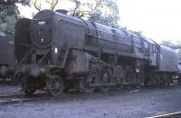 With its connecting rods removed, withdrawn BR Standard class 9F 2-10-0 no 92091 stands outside Carnforth shed in the summer of 1968 awaiting the final trip to the breaker's yard. The 9Fs seemed to epitomise the rush to get rid of steam, being highly regarded locomotives, but withdrawn after very short lives. The lines on which 92091 and the other locos are standing now form part of the West Coast diesel depot and have been partly covered. From the elevated footpath that runs behind the trees, examples of classes 03, 08, 33, 37 and 47 can still usually be glimpsed.  <br><br>[David Hindle //1968]