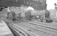 The south end of Carlisle on 17 August 1957 with the Victorian end-screens still in place. 40628 stands on one of the centre roads while 70052 <I>Firth of Tay</I> is at platform 4 with the 1.45pm Glasgow (Central) - Manchester/Liverpool.<br>[Additional: The major station refurbishment which commenced later that year saw the screens demolished and the roof over platform 1 and the west sidings removed. Elsewhere the roof was cut back at either end with the current 'more functional' screens installed. Newly exposed sections of the platforms were equipped with steel-framed canopies. The original supporting walls still stand as a reminder of times past.]<br><br>[Robin Barbour Collection (Courtesy Bruce McCartney) 17/08/1957]