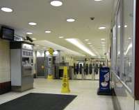 The North Hanover Street entrance to Queen Street station is detached from the main building and serves only the low level platforms with access at their east ends only. It is consequently comparatively quiet, especially at weekends as most of its custom is from commuters and students at Strathclyde University and nearby colleges. It couldn't be quieter here on Saturday 5 February. Note mandatory 'wet floor' cone on the perfectly dry floor. <br><br>[David Panton 05/02/2011]