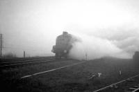 An unidentified A4 heading north out of Newcastle on a foggy day in the 1960s. The train has passed Heaton South Junction [see image 29598] and has just crossed the bridge over the A1058 'Coast Road'. The line running off to the right is a siding serving the Wills cigarette factory.<br><br>[K A Gray //]