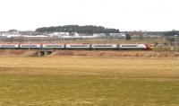 The 13.40 Glasgow Central - London Euston Virgin Pendolino service accelerates south after passing through Carstairs station on 21 March 2011. The high security fencing surrounding the State Hospital runs across the picture beyond the train.<br><br>[John Furnevel 21/03/2011]