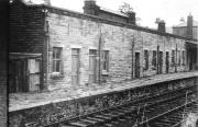 A photograph of the station building at Longridge, probably taken around the time of final closure to goods and parcels in 1967, passenger services having ceased in 1930. This view looks towards the level crossing beyond which lay the goods yard and line to the quarries. The station building continued to be used after closure, principally as a St John Ambulance HQ, and this allowed it to survive until its recent conversion into a cafe and community centre [See image 33685].<br><br>[David Hindle Collection //1967]
