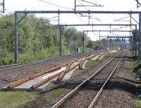 Intermittent short lengths of track for the third line between <br>
Glasgow and Paisley are either in place or, as here, waiting to be <br>
properly bedded in.  This view on 2 May looks east from Hillington West station where the points in the foreground will presumably allow access to the westbound platform.  In the background a new but uncommissioned signal gantry is now in place.<br>
<br><br>[David Panton 02/05/2011]