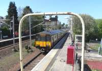 Framed by the 1960s lighting arch at the bottom of the footbridge 318 252 pulls into Hillington East with an all stations Gourock to Glasgow service on 2 May. On the platforms red safety barriers have been placed around holes dug to receive the gantry supports necessary to supply the third track between Glasgow and Paisley, currently under construction.<br><br>[David Panton 02/05/2011]