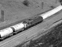 EE Type 4 No. 40 090 brings a train of empties up through the deep cutting at Buxworth in June 1977 bound for the Blue Circle cement works at Hope.<br><br>[Bill Jamieson 11/06/1977]