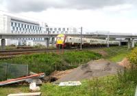 The 09.28 service from Milngavie slowing for stop no 16,  Edinburgh Park, on 31 May 2011.  The train will reach Waverley at 10.57. The pipes, notices, excavated soil etc in the foreground are leftovers from work on a recent gas leak. <br>
<br><br>[John Furnevel 31/05/2011]