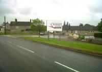 The old station building at Evercreech Junction (left of sign) and the former railway bungalows (right) have survived very well, but the hoarding advertising the industrial estate says far more about the fate of the 'Serene and Delightful'. Their logo is the wrong way round... but that's a small part of the overall problem.<br><br>[Ken Strachan 30/05/2011]