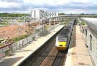 View west through the windows of the station footbridge at Edinburgh Park on 31 May 2011.  Following resolution of the ongoing contractual problems affecting progress on the Edinburgh Tram project work has recommenced, with the area to the left destined to become part of a transport interchange. The ramp climbing to cross the line via the flyover in the background will eventually carry the tram route north through the business park towards Gogar and its ultimate destination at Edinburgh Airport. Meantime the East Coast 07.55 Inverness - London Kings Cross 'Highland Chieftain'  HST heads east through the station.<br><br>[John Furnevel 31/05/2011]