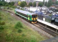 A view from the road above of the 'new' St Johns station on the Bedford to Bletchley line. The vehicle recovery yard on the right contains four Standard cars - probably one of the largest collections anywhere! The train is the 15.55 from Bedford Midland to Bletchley.<br><br>[Ken Strachan 17/06/2011]