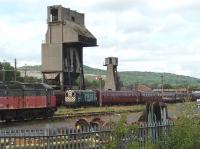 Four of the six DRS Class 20s were removed from storage at Carnforth on 5 July 2011 and returned to Kingmoor for attention and a possible return to service. The view of the yard has therefore opened up again and resident shunter 08485 is seen here on 7 July pulling a rake of WCRC coaches past the coaling tower. 47772 in faded RES livery remains on the storage road with several other locomotives.<br><br>[Mark Bartlett 07/07/2011]