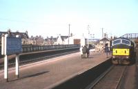 The NBL Type 2s were, for a few years following dieselisation, the staple locomotive on Buchan line trains. In this photograph, having attached a portion off the 3.20pm ex-Peterhead [see image 37410], the 3.15pm train from Fraserburgh (from which the photograph is taken) is pulling away from Maud Junction to continue its journey south to Aberdeen. Meantime, the driver of the Peterhead train is about to rejoin his locomotive in order to carry out some shunting operations.<br><br>[Frank Spaven Collection (Courtesy David Spaven) 01/05/1965]