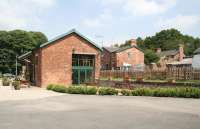 Part of 'Old Station Yard' at Masham, North Yorkshire, photographed on 27 June 2011, in use as a caravan and camping park. The restored goods shed is now a cafe. Beyond the fence, the former station master's house is the home of the family operating the site. A single storey station building adjoins the house although the platforms have been infilled. Former railway cottages stand in the right background. The corrugated iron-roofed garages to the right were adapted from the old coal-drops. Opened in 1875, the single line Masham branch left the Leeds Northern at Melmerby North Junction and was served by 4 trains a day from Ripon. Masham lost its passenger service in 1930, although the line itself survived until 1963.<br><br>[John Furnevel 27/06/2011]