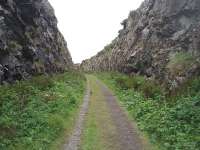 Trackbed level view through the Portpatrick headland cutting looking, at this point, south south east. From the station the line climbed steeply and turned through almost 180 degrees to head inland towards Colfin and Stranraer. [See image 34253] for the view of this location from the cliff top.<br><br>[Mark Bartlett 27/05/2011]