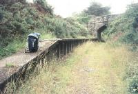 Platform remains at Dunmere Halt, Cornwall in July 1980,  looking east along the trackbed towards the former terminus at Bodmin North. The station and branch closed beyond Dunmere Junction (a short distance behind the camera) in January 1967. [Note the station running-in board (presumably in concrete) broken in half, part on the platform, with the end of the name resting in what was the four-foot.] <br><br>[Ian Dinmore /07/1980]