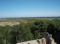 A distant view of the trackbed of the long closed Lossiemouth branch, running straight across the flat landscape. The town itself can be seen on the horizon in this view looking north from the top of ruined Spynie Palace on the outskirts of Elgin. The branch trackbed is now a footpath for most of its length. <br><br>[Mark Bartlett 02/07/2011]