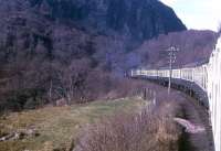 A Type 2 hauling eight vehicles battles its way up the 1 in 50 to Raven's Rock summit, between Achterneed and Garve, in the spring of 1971. The train is the 10.30am Inverness - Kyle of Lochalsh. The shot was used in a publicity brochure published by BR - surprisingly, as closure notices had already been posted - to promote the 1972 tourist season.<br><br>[David Spaven //1971]