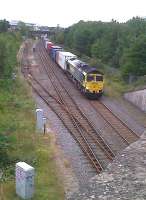 View north east at Three Spires Junction on 30 August 2011, with Freightliner 66542 approaching Coventry from Nuneaton on a container train. The line to the left serving the Prologis Industrial Park looks a little underused. Coventry City's Ricoh stadium in the background, standing alongside the line, is woefully under-provided with car and coach parking. A new station here should be completed by December 2013.<br><br>[Ken Strachan 30/08/2011]