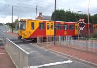 Having just left Newcastle Airport, this Tyne and Wear Metro train reaches its first stop in a matter of moments, crossing Callerton Lane on the level at the western approach to the station. Callerton Parkway opened as part of the extension to Newcastle Airport in 1991. Besides the station car park for Metro customers here, there are long-term parking facilities and hotel accommodation for Airport passengers.<br><br>[Andrew Wilson 11/09/2011]