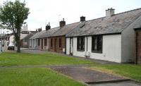 View south west along the B7020 towards Lochmaben town centre (and the Railway Inn) on 20 May 2008. The white bungalow on the right stands on the old trackbed, with the platforms once running across the centre of the picture. In railway days the road on the left passed over the station on a bridge slightly further to the east (the old route is now occupied by the houses of Station Court). No trace remains of bridge or station. [With thanks to Alan Hannah] [See image 21410]<br><br>[John Furnevel 20/05/2008]