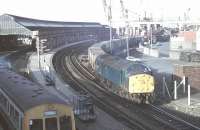 English Electric Class 40 1Co-Co1 No. 40004, one of the ten pilot scheme locos that started life on the Great Eastern main line in 1958, draws a long train out of Holyhead container depot passing the passenger station and an arriving Met-Cam DMU. 40004 continued in main line use for a further three and a half years before withdrawal in September 1984 after twenty six years service. It was cut up at Crewe two years after that.<br><br>[Mark Bartlett 15/03/1981]