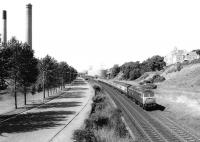 A Class 47 takes a Glasgow - Aberdeen train away from Dundee towards Stannergate in 1981, passing Carolina Port power station on the left. The chimneys were demolished in April 1984, a year after closure of the oil-fired power station.<br><br>[John Furnevel 11/08/1981]