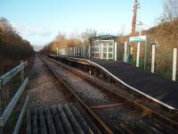 The setting sun illuminates the remote halt of Dolgarrog, separated from the village it serves by the River Conwy and only accessible from there by footbridge. View north towards Tal-y-Cafn on a Sunday afternoon. Blaenau Ffestiniog trains only run Monday to Saturday so there is a thin film of rust on the rails.<br><br>[Mark Bartlett 28/11/2011]