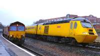 EWS 66193 pulls past Kilmarnock platform 3 on 19 December with a rake of empty hoppers bound for Crowbandsgate. Meanwhile, NR Measurement Train 43062 <I>'John Armit'</I> bides its time on the middle road.<br><br>[Colin Martin 19/12/2011]